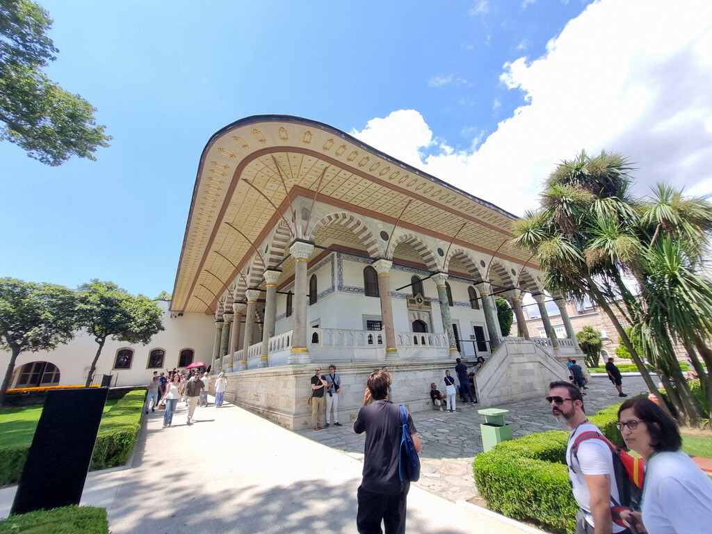 The Audience Hall at the entrance to the Third Courtyard of Topkapı Palace, seen in a wide-angle view with its elegant columns and visitors gathered around the pavilion. photo by Serhat Engul